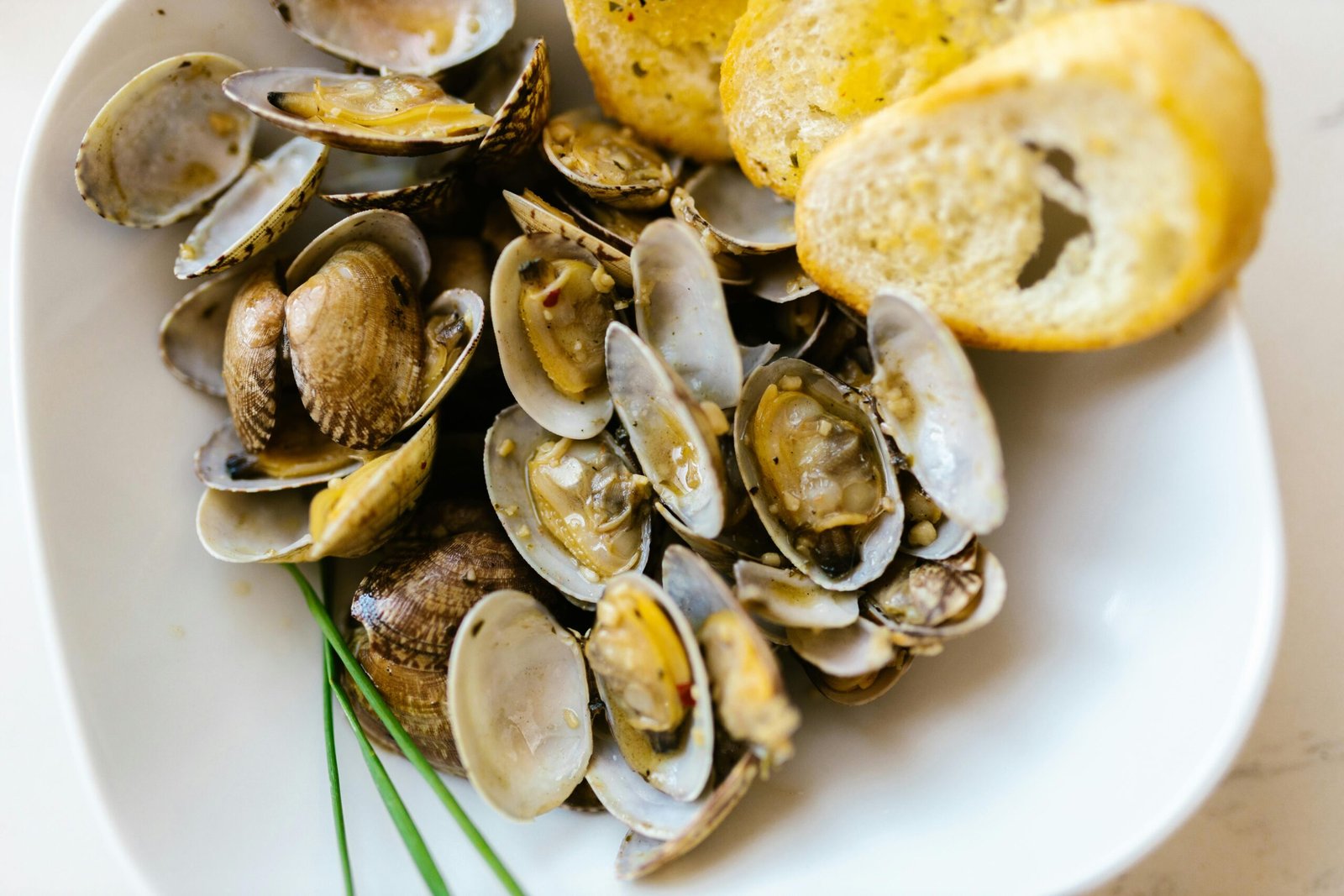 A close-up of delicious steamed clams served with crispy toasted bread.