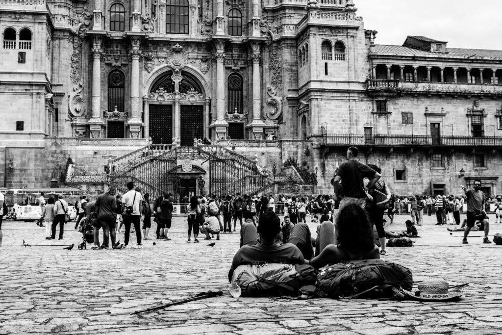 Monochrome scene of pilgrims resting near Santiago de Compostela Cathedral in Spain.