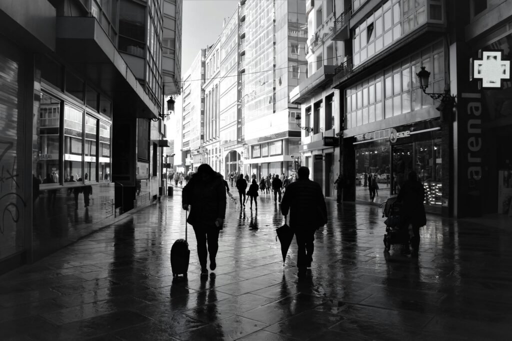 Monochrome street view in A Coruña, Spain with people walking under modern buildings.