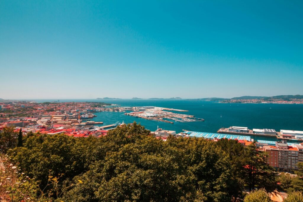 Aerial panoramic view of Vigo port, Spain, showcasing vibrant cityscape and blue sea under a clear sky.