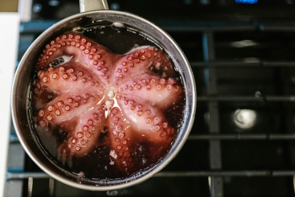 Close-up of octopus tentacles boiling in a pot on a stove.