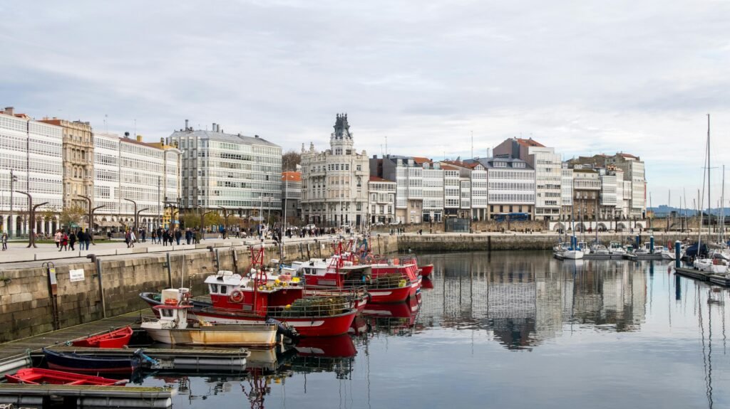 View of the picturesque harbor in A Coruña, Spain, with vibrant boats and urban backdrop.