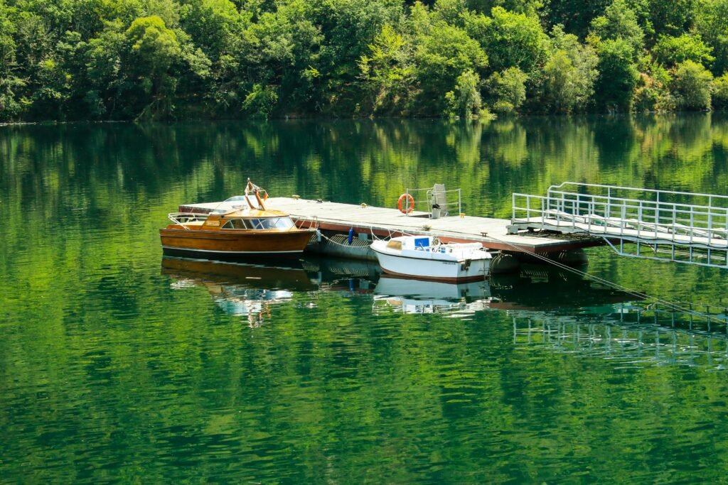 Peaceful scene of boats on a pier surrounded by lush greenery in Sober, Galicia.