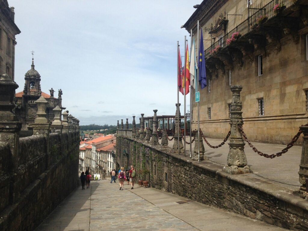 Elegant street view in Santiago de Compostela with stone architecture and flags.