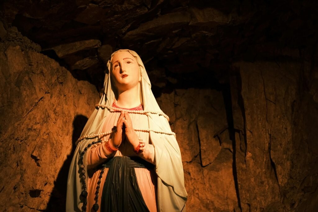 Beautifully lit statue of Virgin Mary in a cave, embodying serenity and grace.