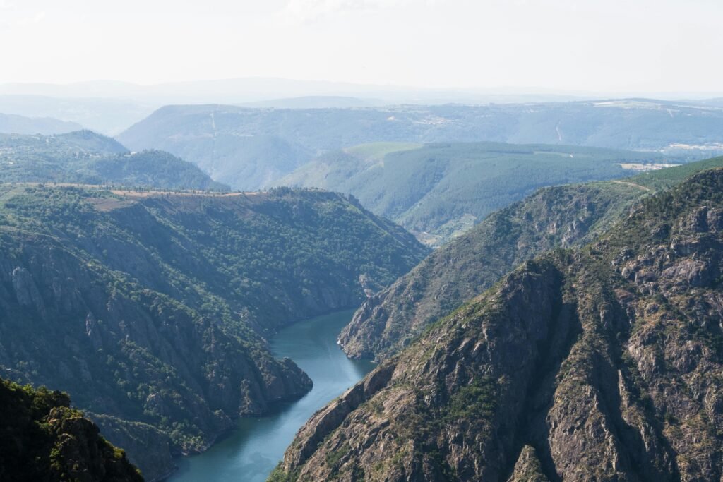 Breathtaking aerial view of Ribeira Sacra canyon with lush greenery and winding river.